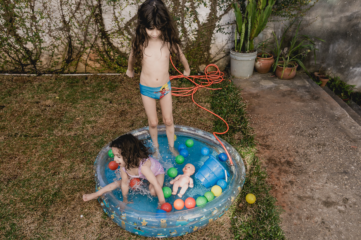 irmãos brincando na piscina do quintal de casa