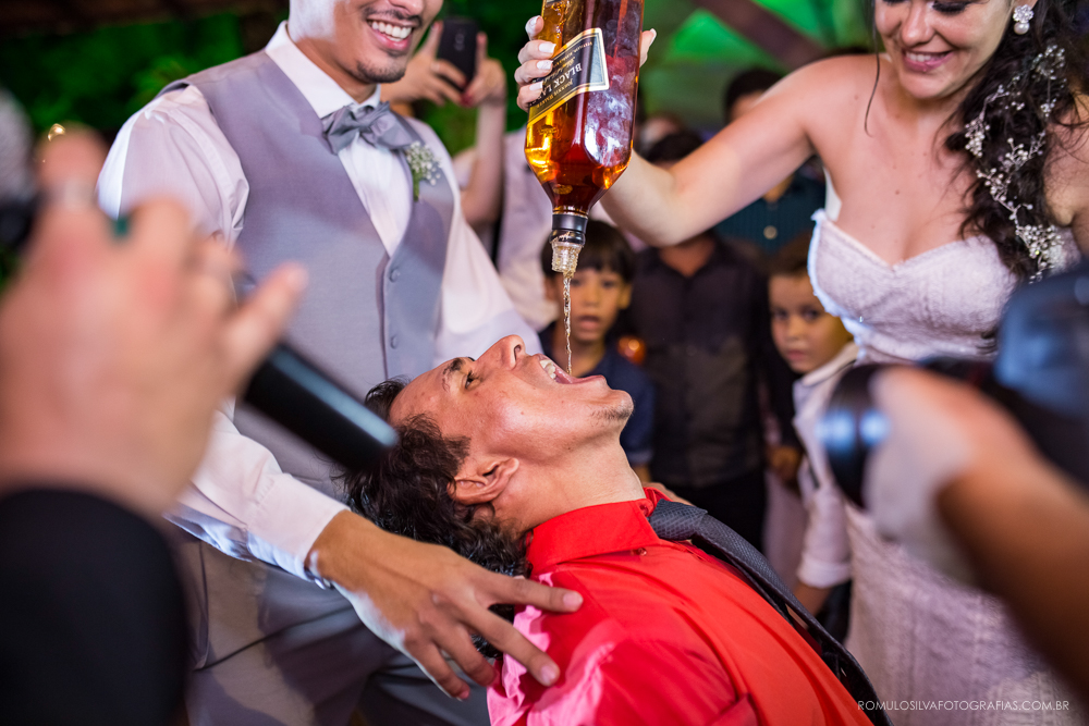 noiva virando o uísque na boca de convidado em festa de casamento ao ar livre 