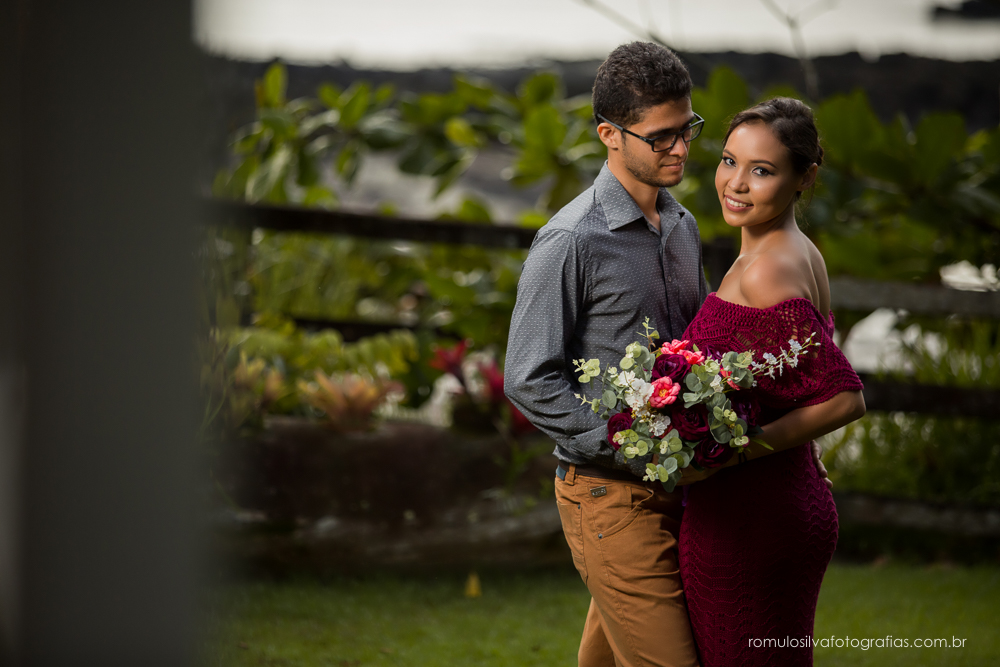 casal de noivos, Dulci e Glaisson, apaixonados, em uma pose linda, romântica, com um bouque em flores artificiais em uma paisagem linda e na beira da praia, no Chalé da Zuzu em Mosqueiro - PA