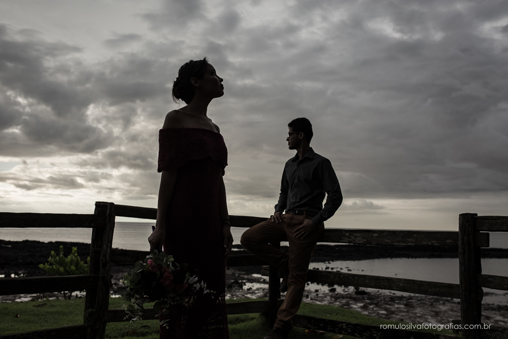 casal de noivos, Dulci e Glaisson, apaixonados, em uma pose linda, romântica, com um bouque em flores artificiais em uma paisagem linda e na beira da praia, no Chalé da Zuzu em Mosqueiro - PA