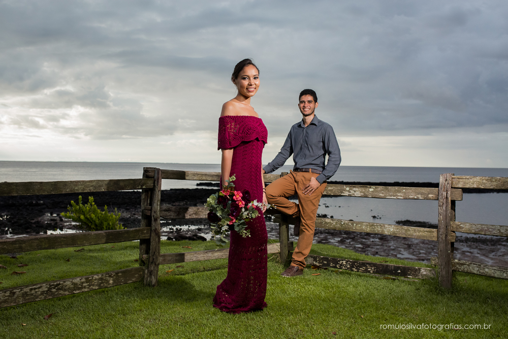 casal de noivos, Dulci e Glaisson, apaixonados, em uma pose linda, romântica, com um bouque em flores artificiais em uma paisagem linda e na beira da praia, no Chalé da Zuzu em Mosqueiro - PA
