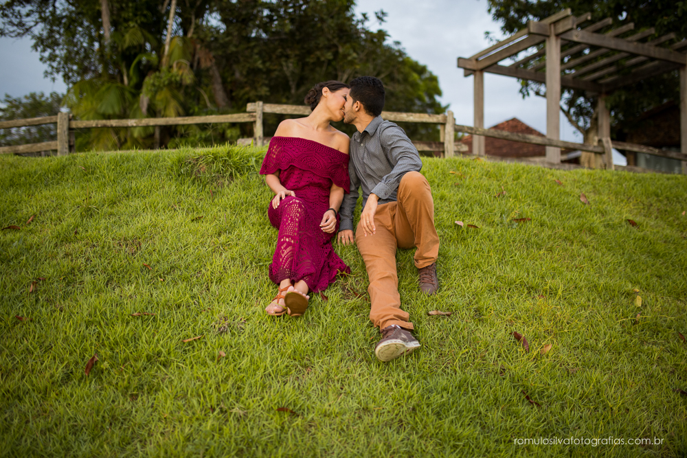 casal de noivos, Dulci e Glaisson, apaixonados,sentados na grama, com um bouque em flores artificiais em uma paisagem linda e na beira da praia, no Chalé da Zuzu em Mosqueiro - PA
