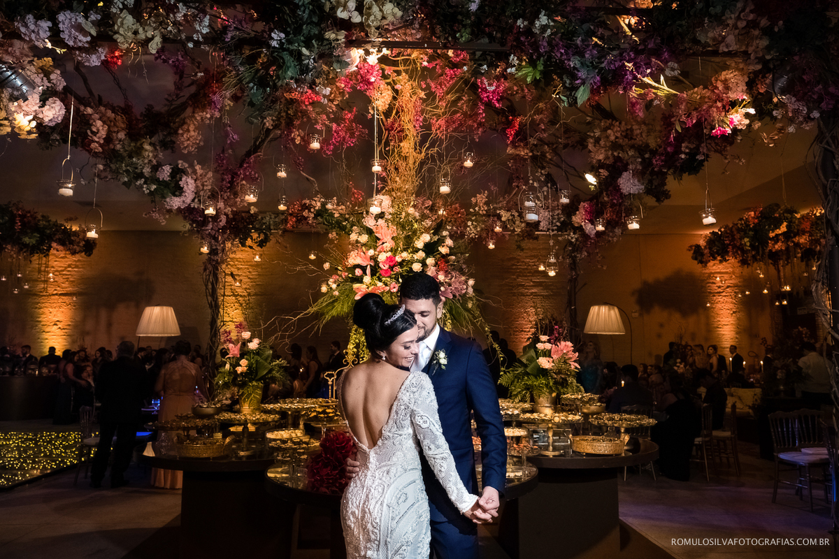 retrato dos noivos andré e verena na frente da mesa de doces na recepção usina