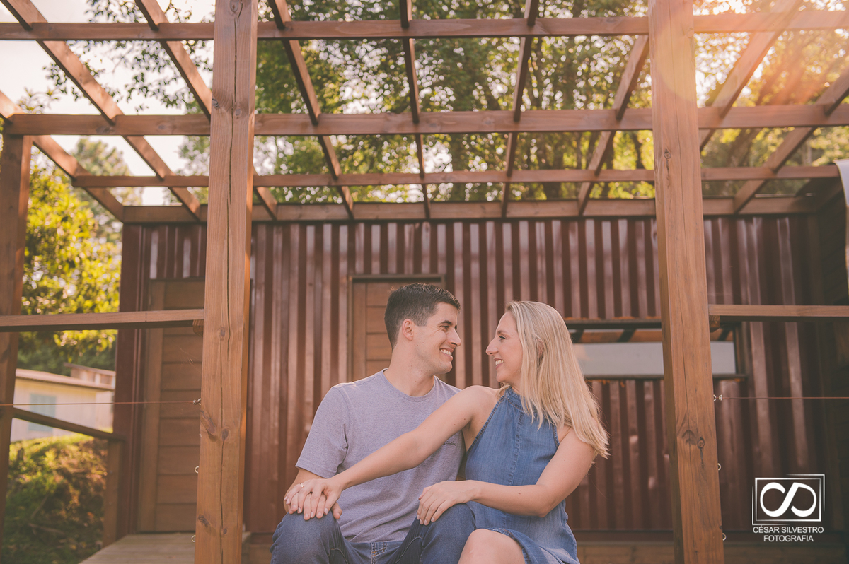 casal de noivos sentados em um deck com o sol ao fundo