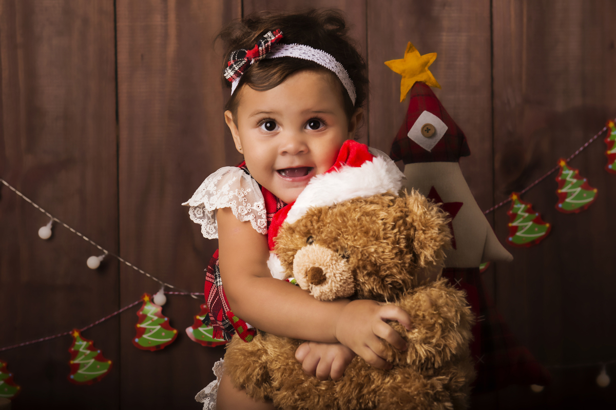 Ensaio fotográfico de Natal com roupas temáticas com crianças brincando no quartinho do Papai Noel com cama brinquedos arvore de natal presentes 