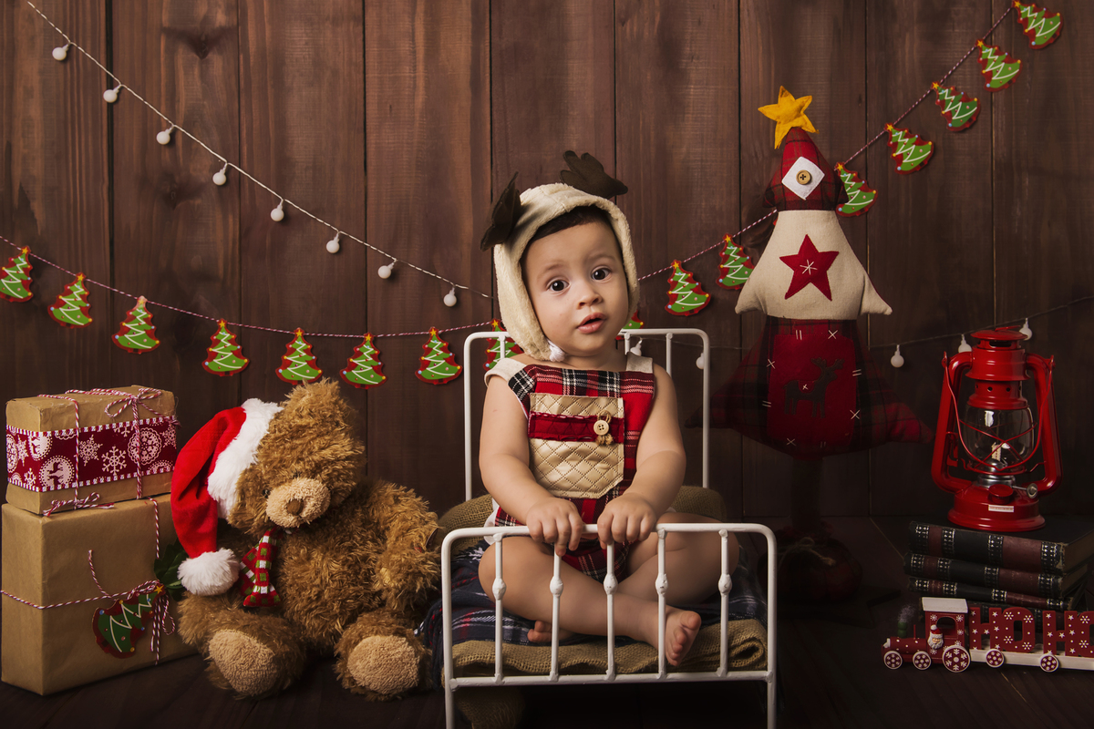 Ensaio fotográfico de Natal com roupas temáticas com crianças brincando no quartinho do Papai Noel com cama brinquedos arvore de natal presentes 