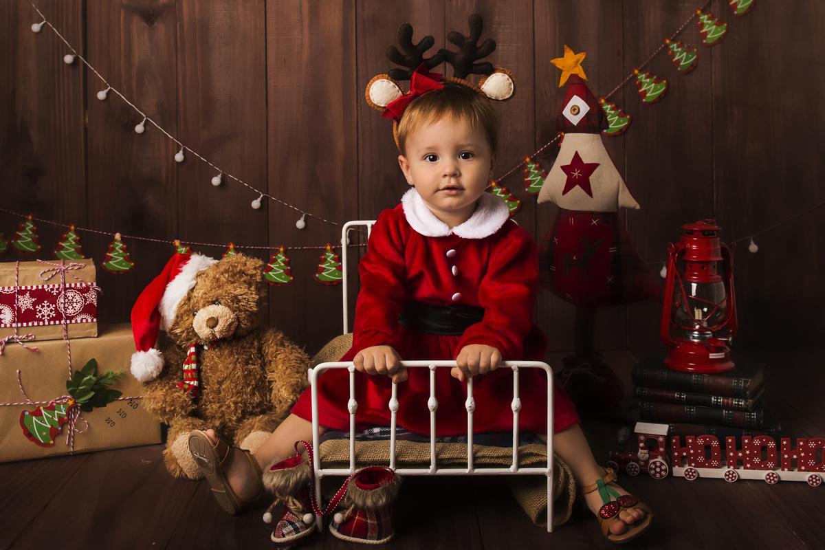 Ensaio fotográfico de Natal com roupas temáticas com crianças brincando no quartinho do Papai Noel com cama brinquedos arvore de natal presentes 