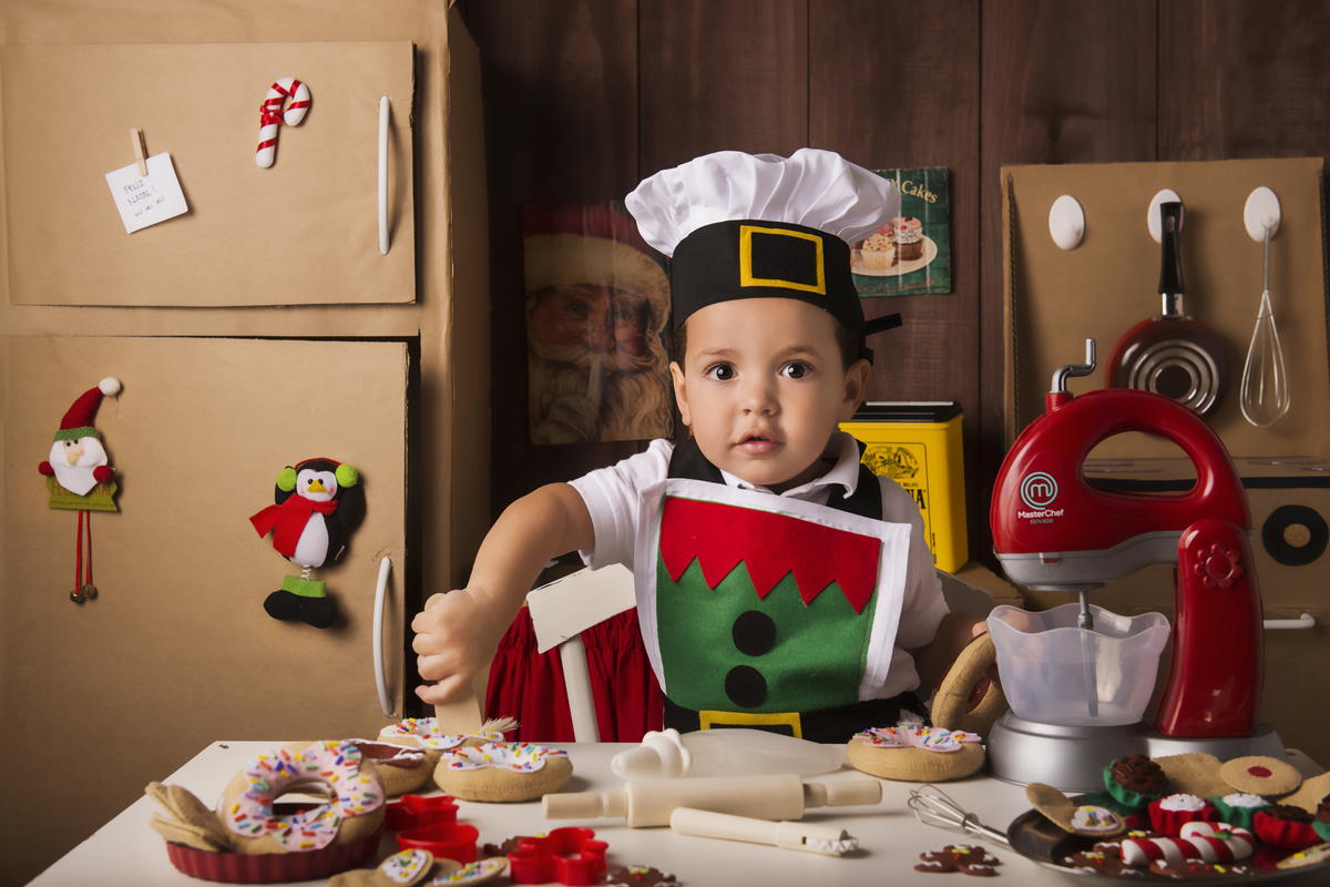
Ensaio fotográfico de Natal com roupas temáticas com crianças brincando de serem chefs de cozinha cenário temático de natal de cozinha com papai noel e comidas mini cozinha para crianças e bebês

