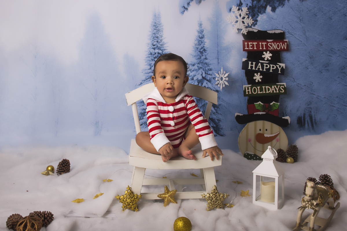 Ensaio fotográfico de Natal com roupas temáticas com crianças brincando na neve com trenó, rena e brinquedos polo norte