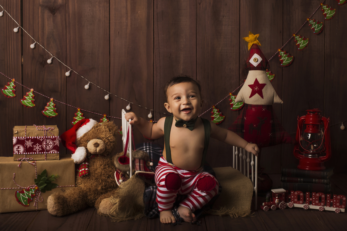 Ensaio fotográfico de Natal com roupas temáticas com crianças brincando no quartinho do Papai Noel com cama brinquedos arvore de natal presentes 