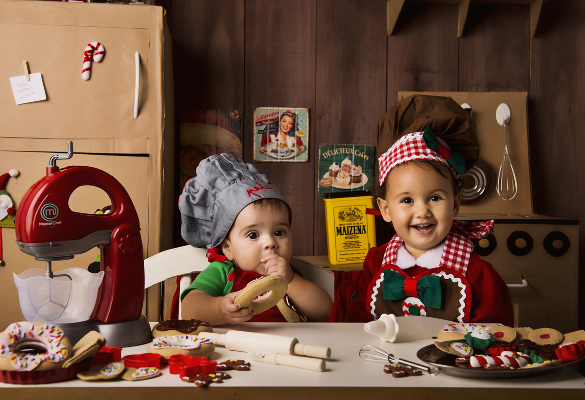 
Ensaio fotográfico de Natal com roupas temáticas com crianças brincando de serem chefs de cozinha cenário temático de natal de cozinha com papai noel e comidas mini cozinha para crianças e bebês
