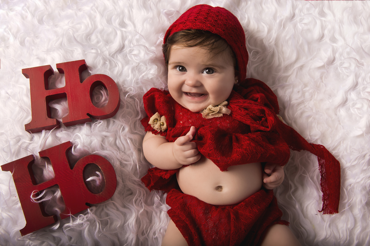 Ensaio fotográfico de Natal com roupas temáticas com crianças brincando na neve com trenó, rena e brinquedos polo norte