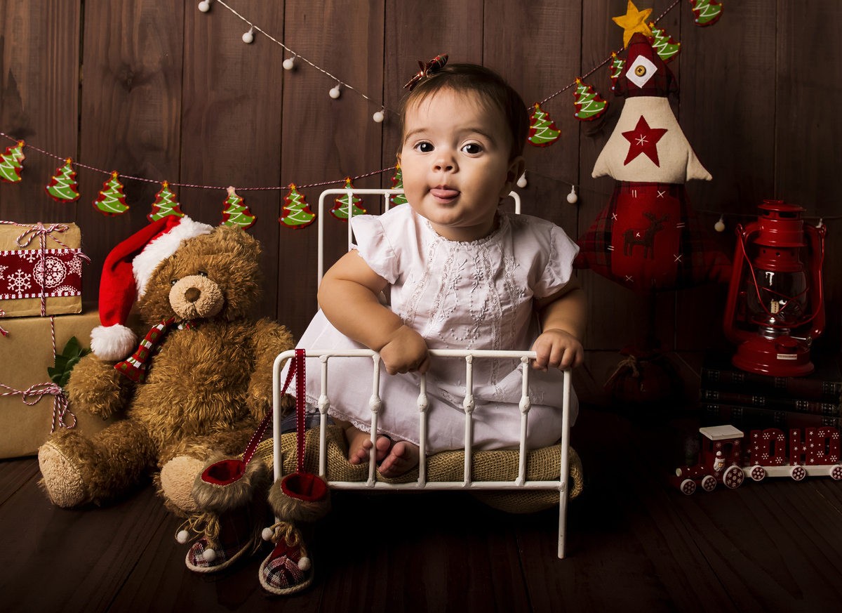 Ensaio fotográfico de Natal com roupas temáticas com crianças brincando no quartinho do Papai Noel com cama brinquedos arvore de natal presentes 