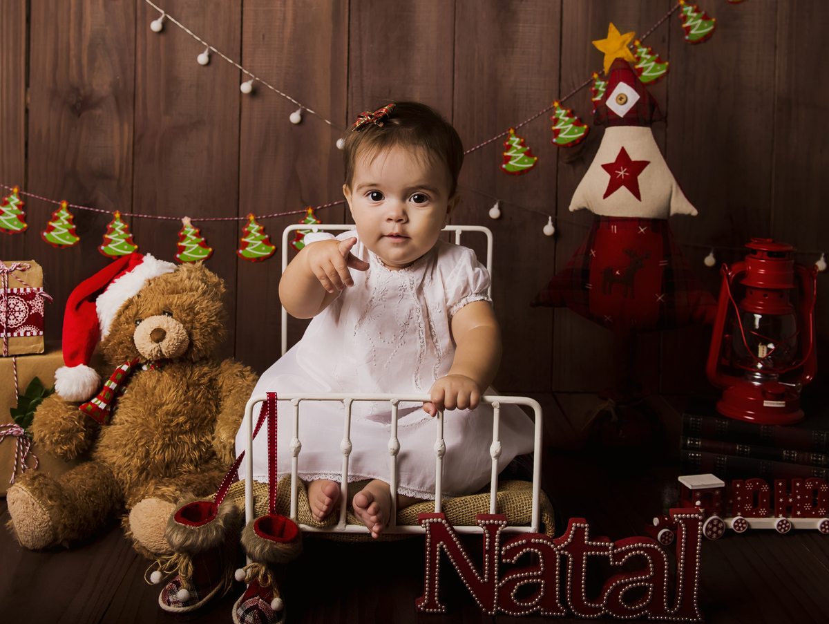 Ensaio fotográfico de Natal com roupas temáticas com crianças brincando no quartinho do Papai Noel com cama brinquedos arvore de natal presentes 