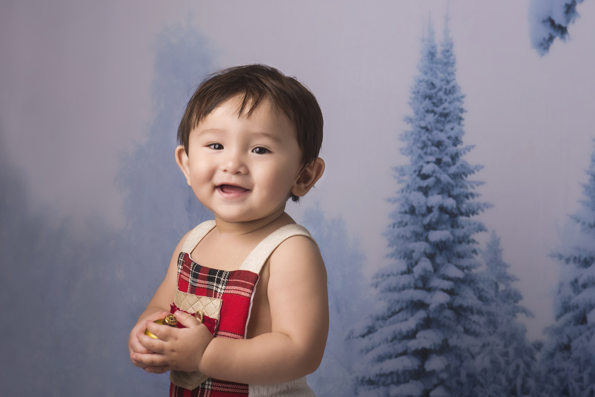 Ensaio fotográfico de Natal com roupas temáticas com crianças brincando na neve com trenó, rena e brinquedos polo norte