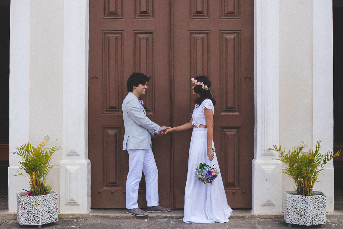 casal na porta da igreja de mãos dadas depois da cerimônia.