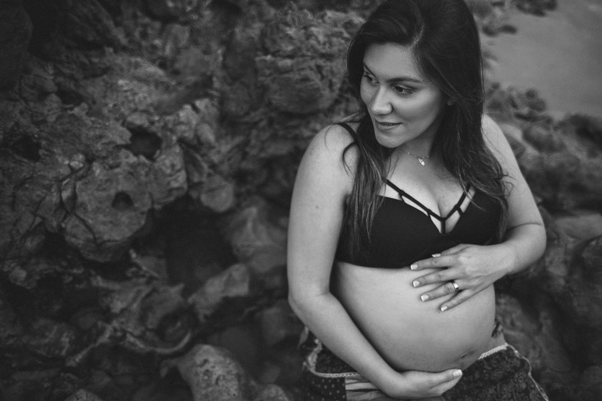 gestante olhando para o lado e segurando a barriga