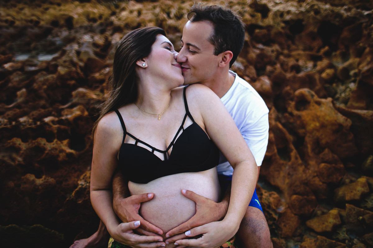 casal se beijando, mulher grávida e marido pegando na barriga.