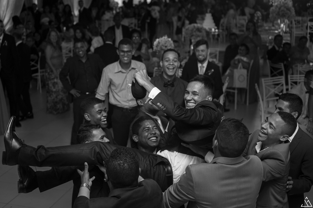 noivo sendo jogado pra cima pelos seus amigos na festa de casamento.