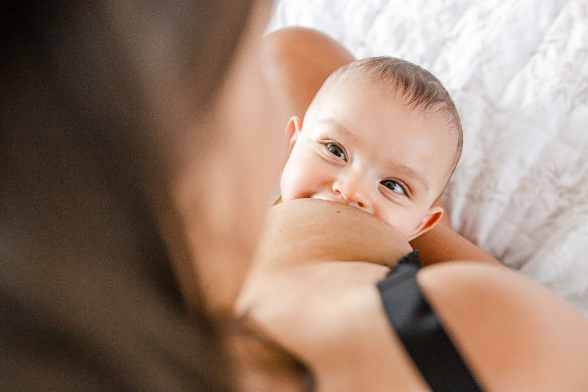 bebê olhando pra mãe enquanto ela amamenta.