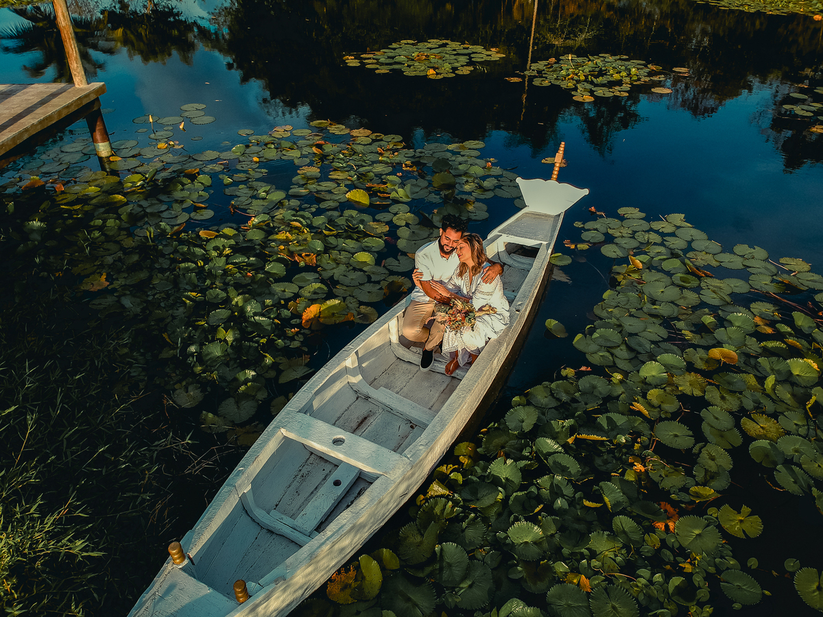 foto aérea com drone de casal no barco num lago cheio de vitória régias