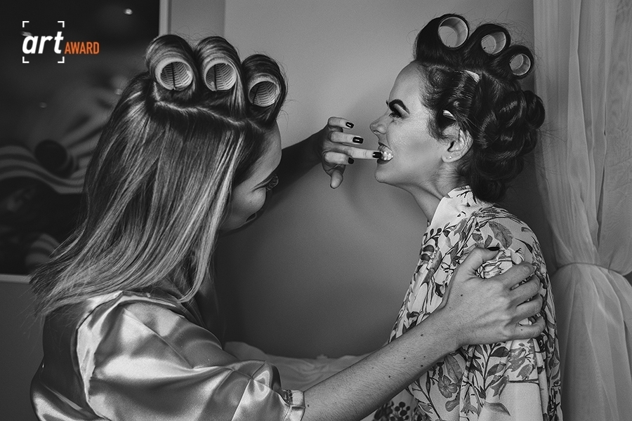 Foto de casamento premiada pela Fineart association. Jessica Mendes fotografia. fotografa de casamento premiada. foto premiada da noiva com irmã limpando o dente sujo de batom.