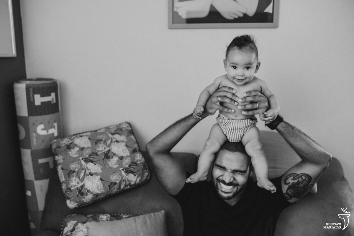 pai coloca o filho sentado em sua cabeça que sorri