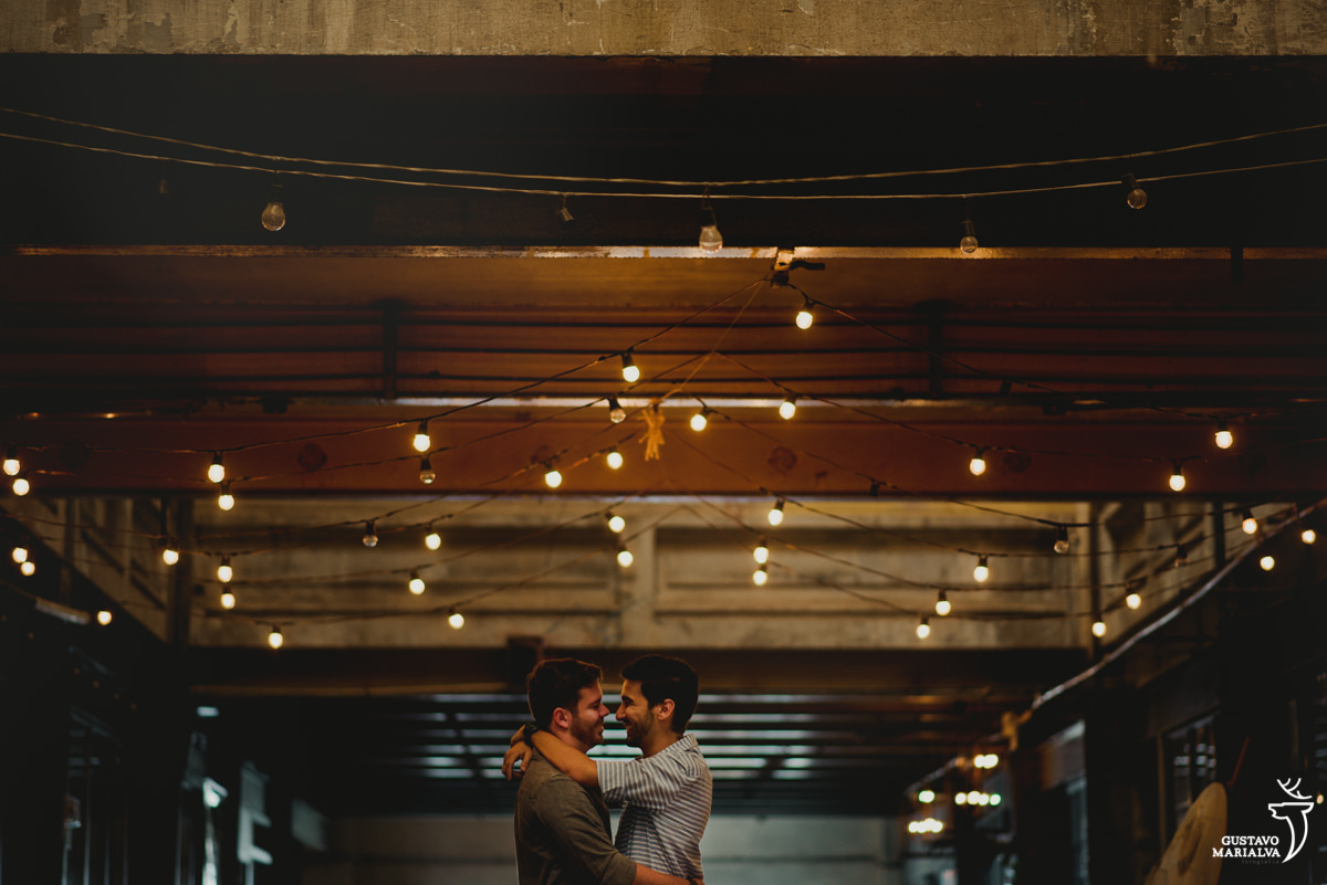 casal gay abraçados com gambiarras ao fundo