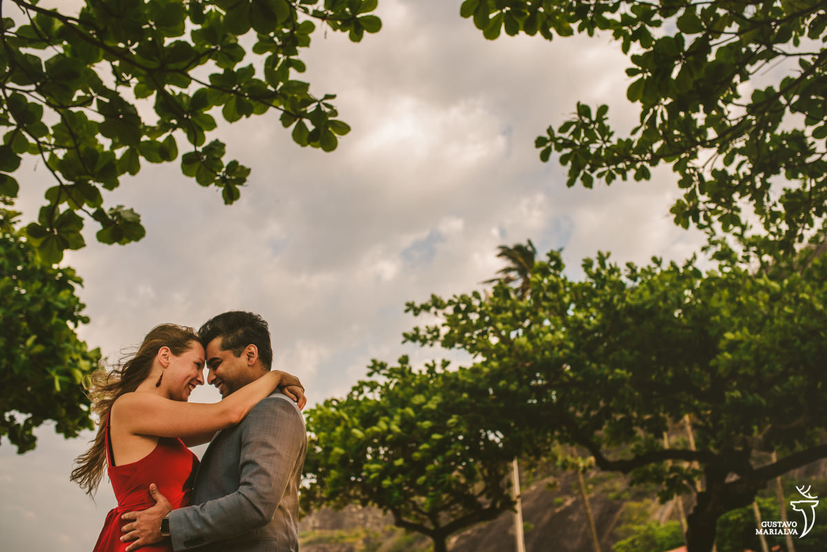 casal se abraça com as árvores como plano de fundo e o dia nublado