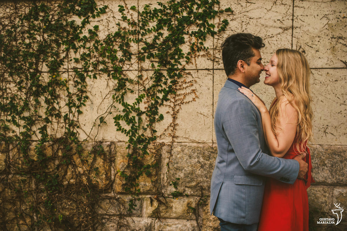namorados se abraçam em frente a parede com grama e sorriem