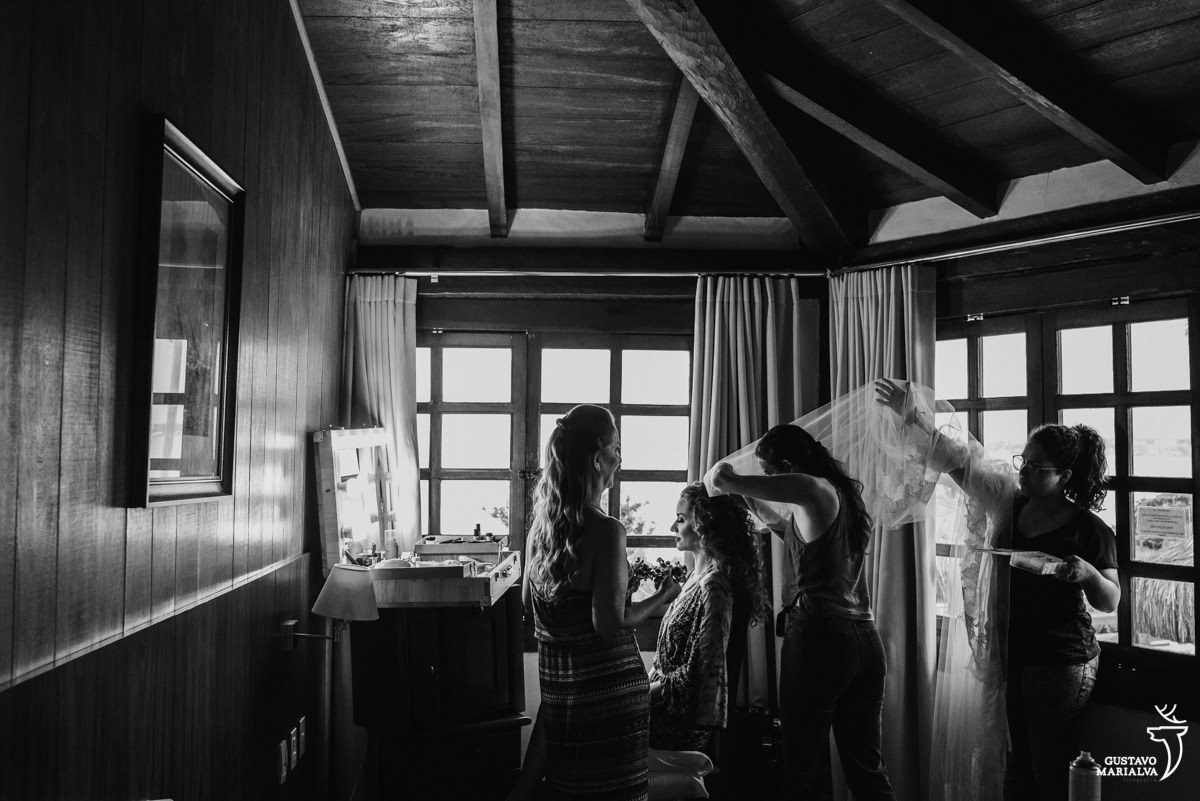 maquiadora coloca o véu na noiva enquanto é observada pela mãe