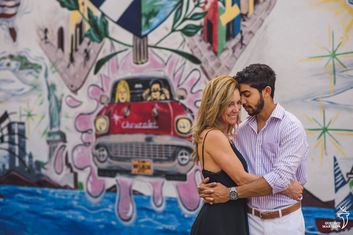 casal se abraça com grafite de carro cubano ao fundo