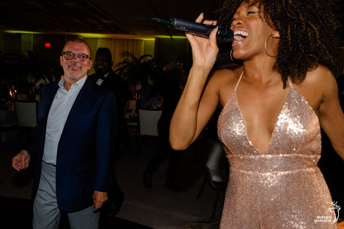 homem dança e observa cantora usando macacão dourado