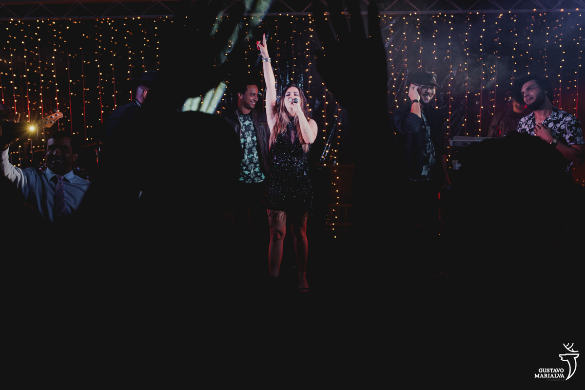 cantora levanta o braço e grita enquanto convidados batem palma