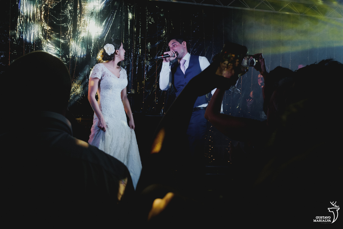 noivos cantam juntos no palco e convidados filma com o celular