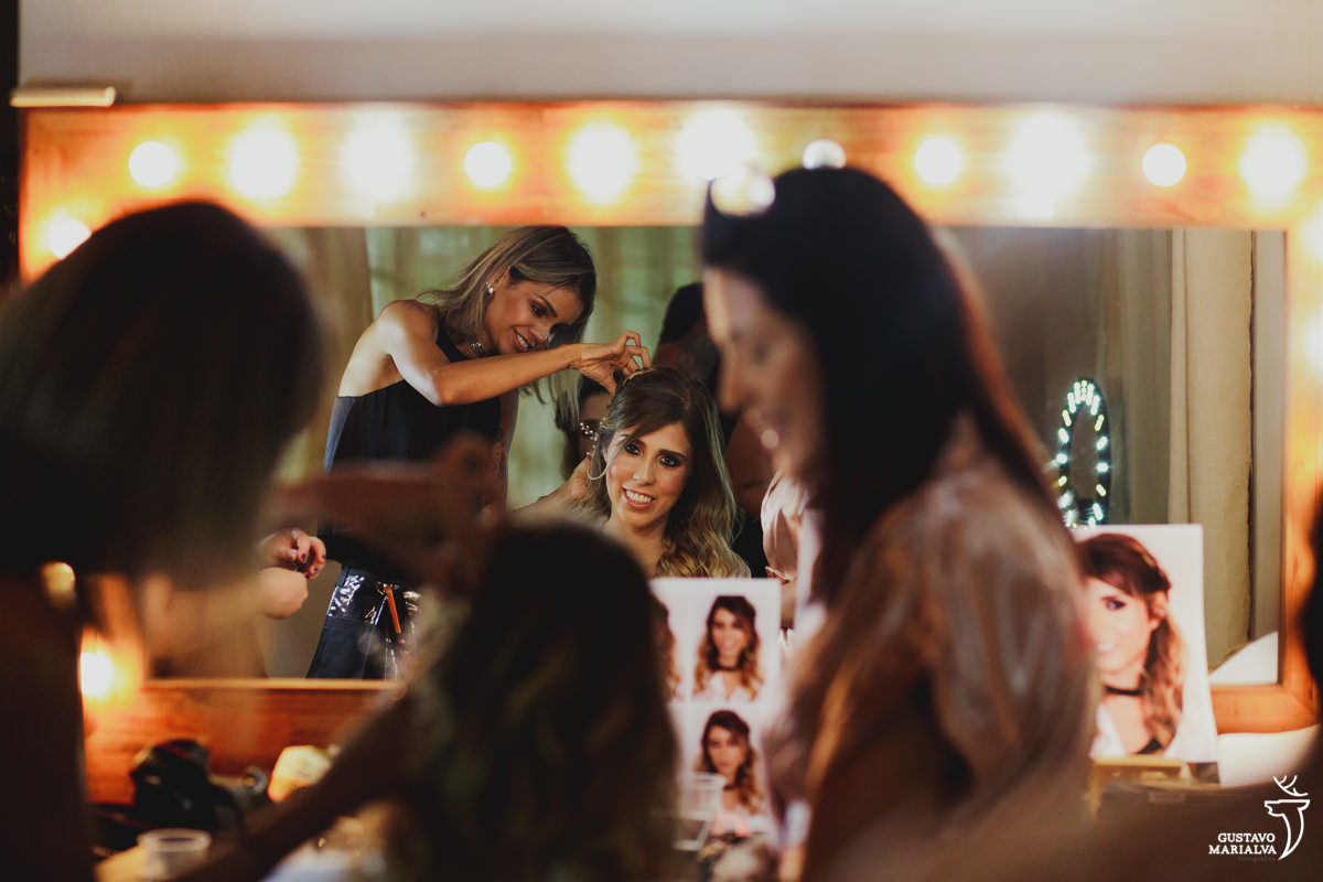 noiva sorri ao se olhar no espelho enquanto conversa com a mãe