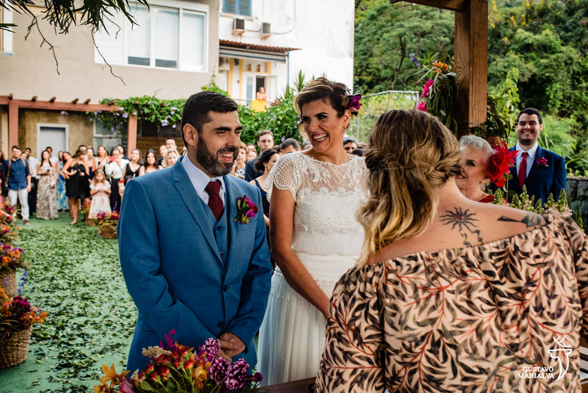 noiva sorri olhando para o noivo durante a cerimônia de casamento