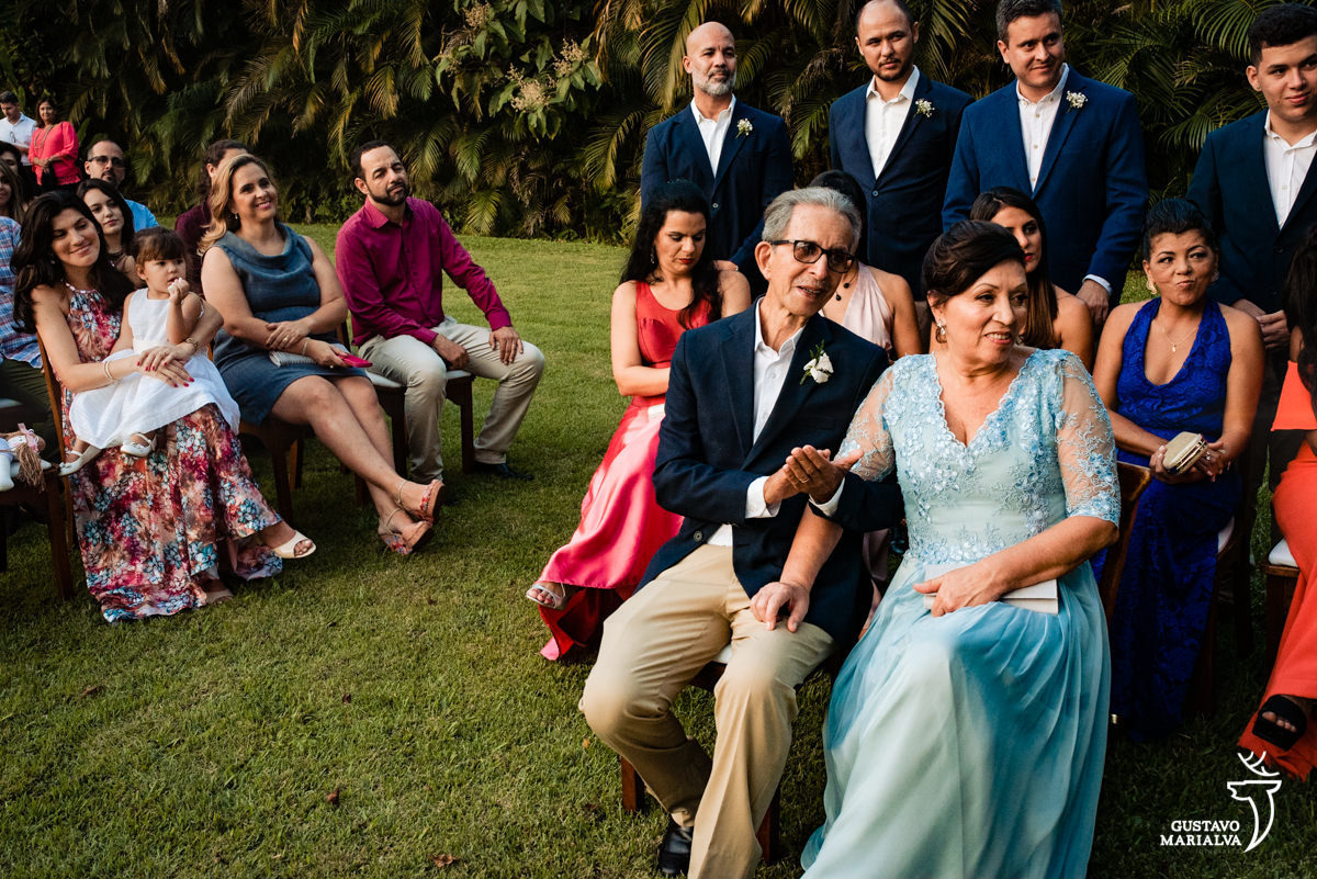 convidados observam emocionados a cerimônia de casamento enquanto menina chupa o dedo