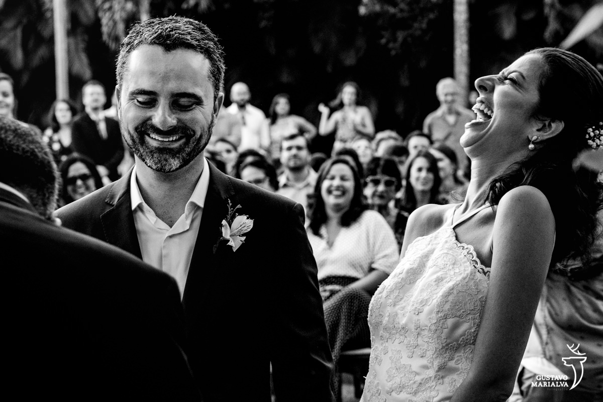 noiva gargalha olhando para cima enquanto noivo sorri durante a cerimônia de casamento