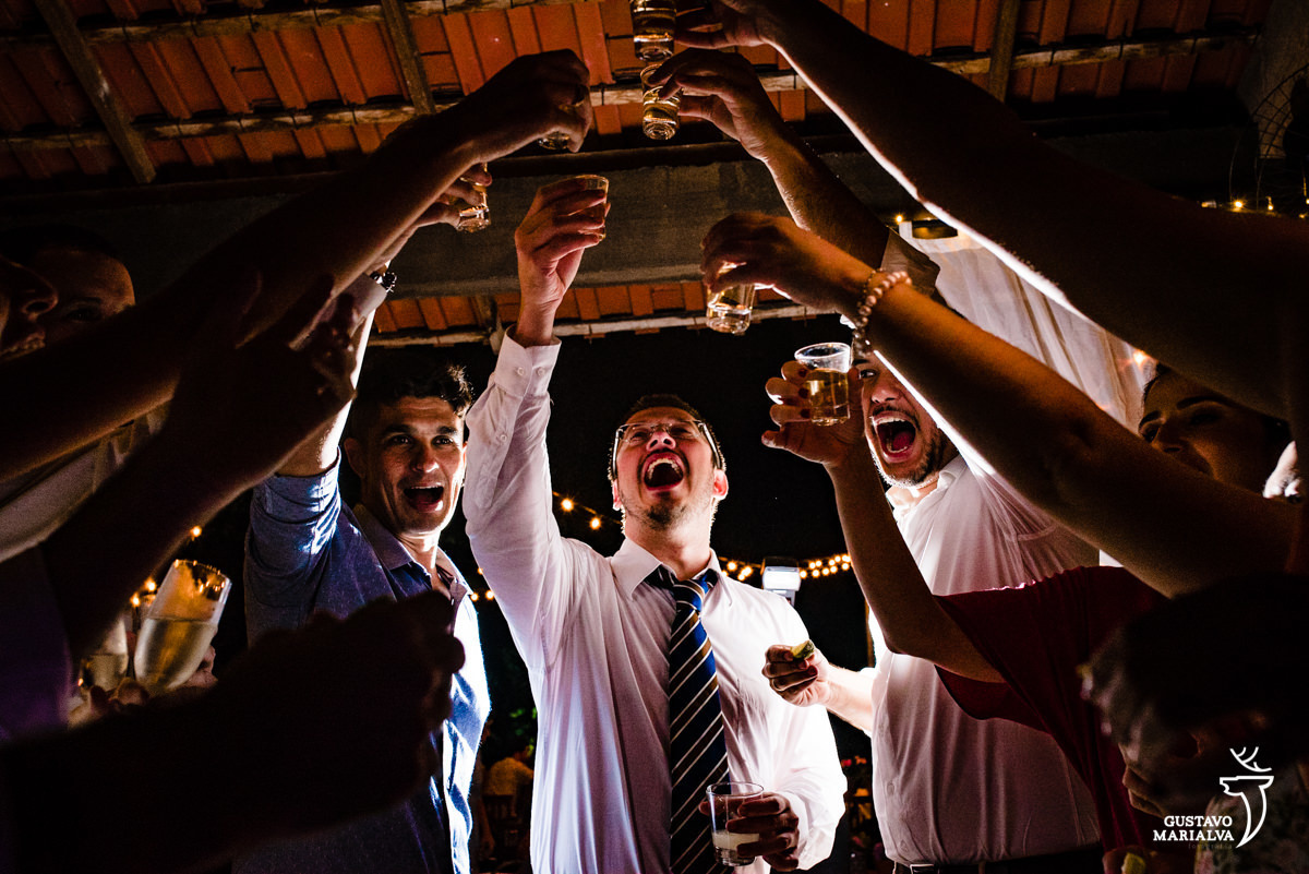 amigos brindam com shots de tequila levantando os braços para cima