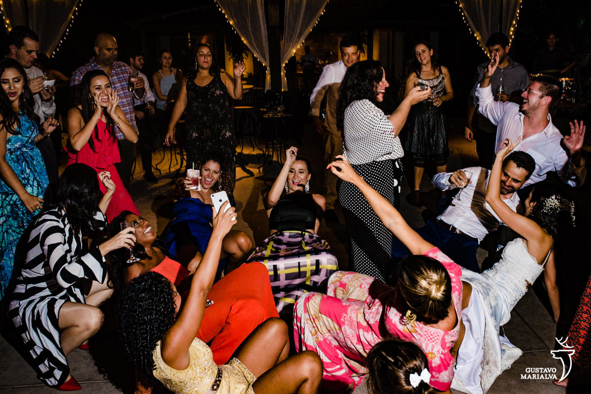 noivos e amigos dançam deitados no chão com as mãos para cima