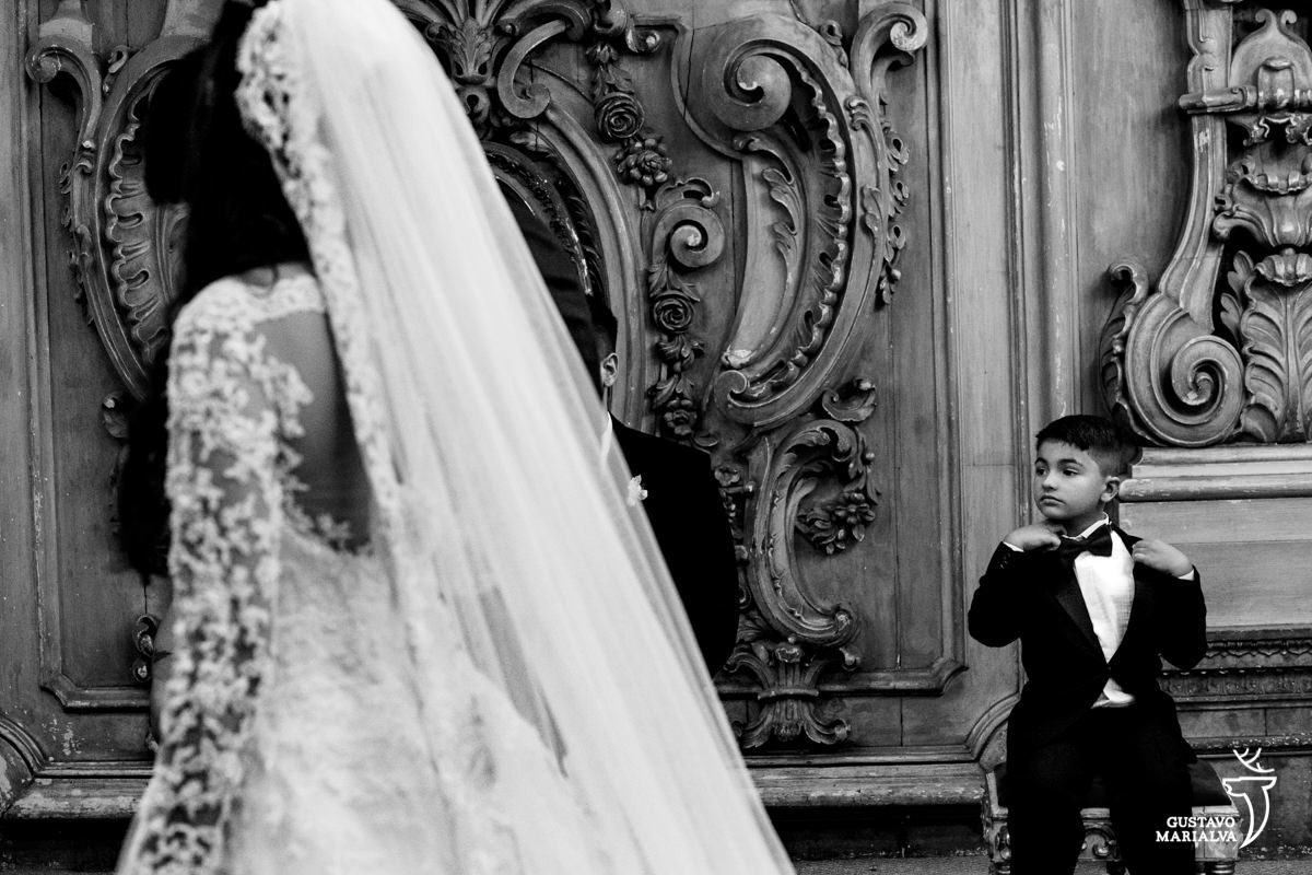 pajem usando smoking ajeita a gravata borboleta durante a cerimônia de casamento