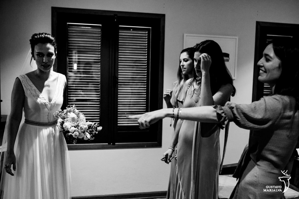 noiva segurando buquê de noiva sorri enquanto amigas olham emocionadas