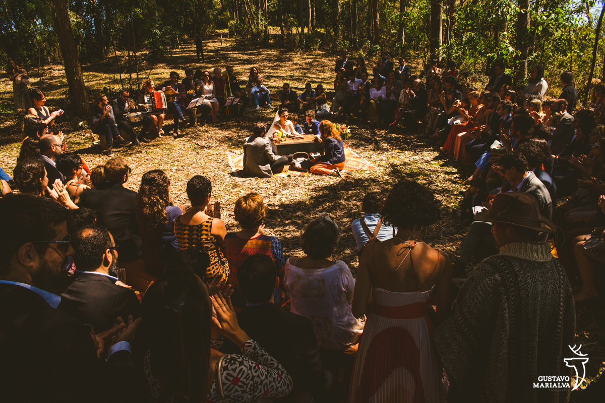 convidados em volta da cerimônia acompanhando a cerimônia de casamento