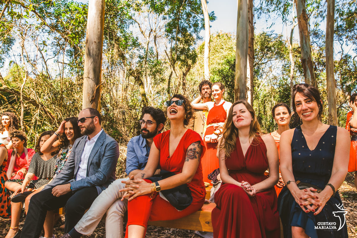 convidados sorriem durante a cerimônia e casal se abraça emocionado