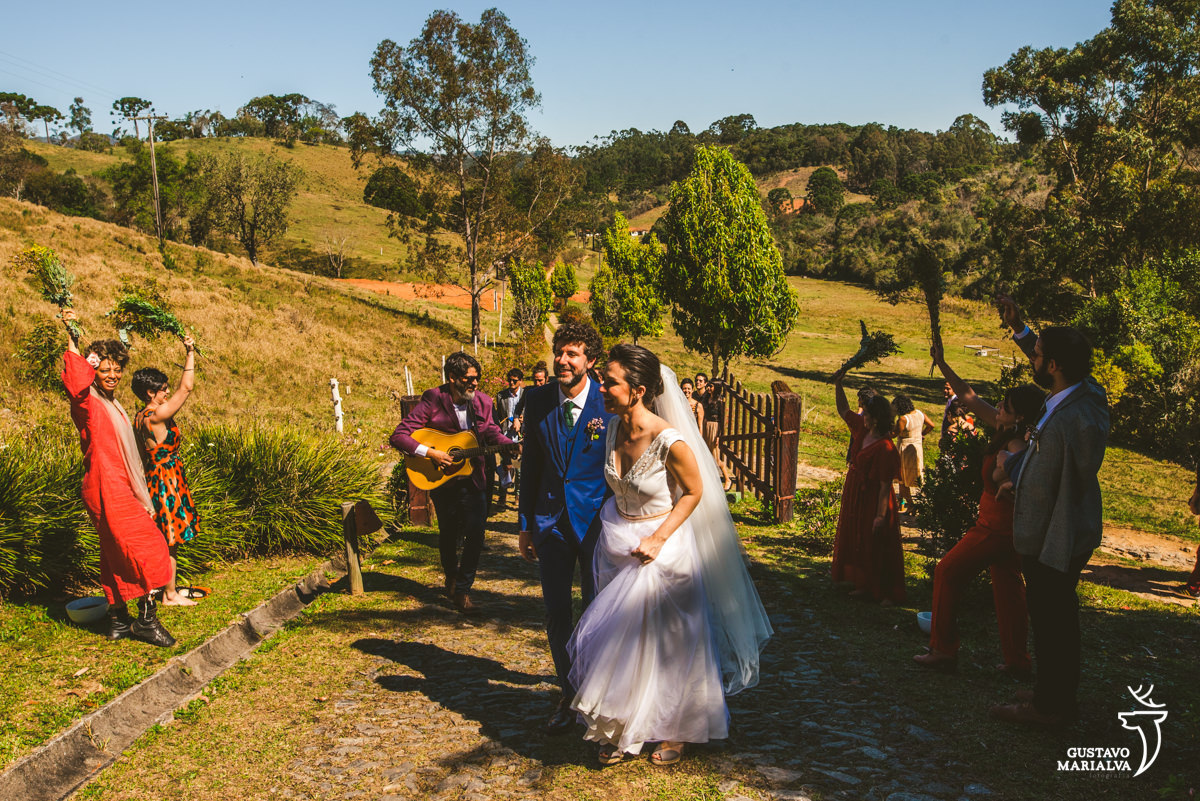 noivos andam de mãos dadas enquanto amigos jogam água neles