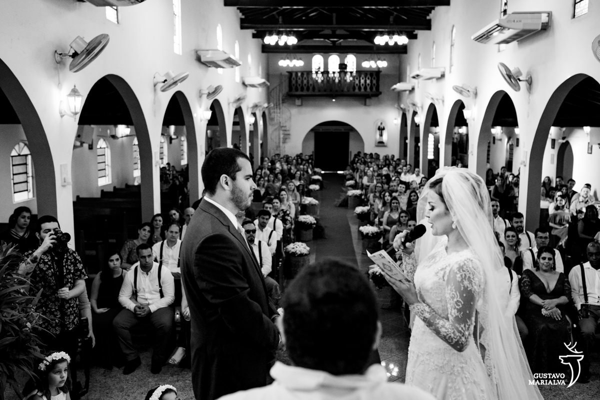 noiva le os votos para o noivo enquanto são observados pelos convidados