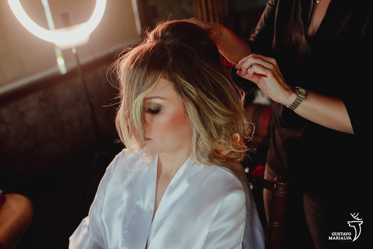 noiva com a franja na frente do rosto arruma o cabelo durante o making of do casamento