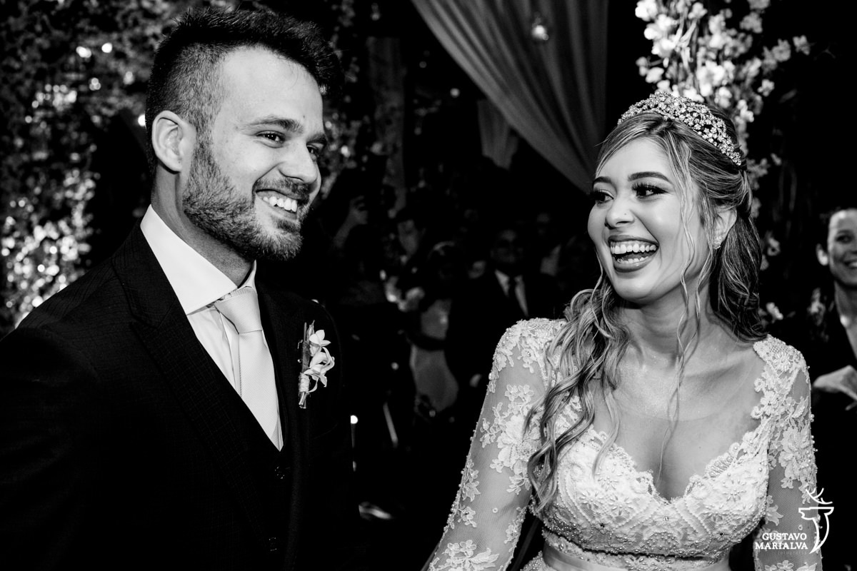 noiva usando grinalda de brilhantes olha para o noivo e sorri