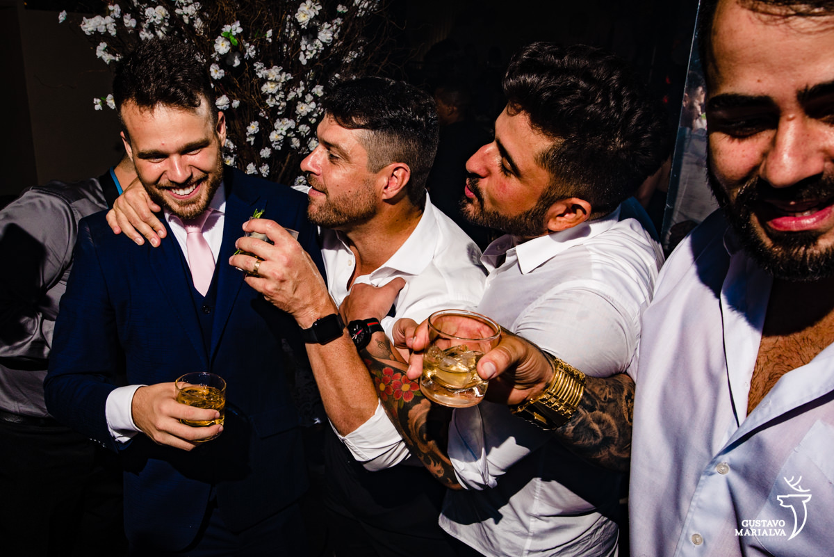 noivo usando terno azul é abraçado por amigos 